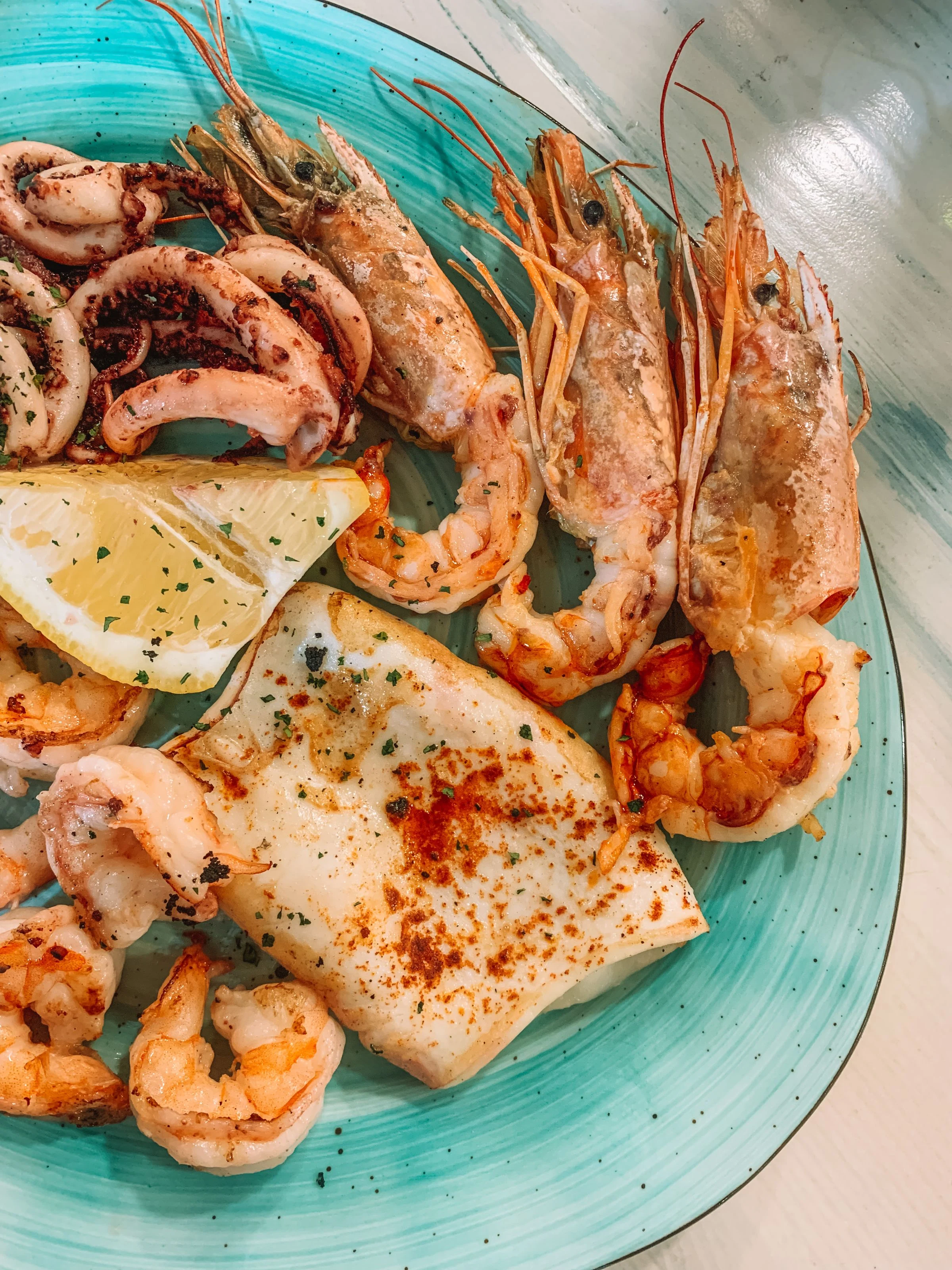 Un misto di pesce alla piastra: calamaro e gamberoni, col limone