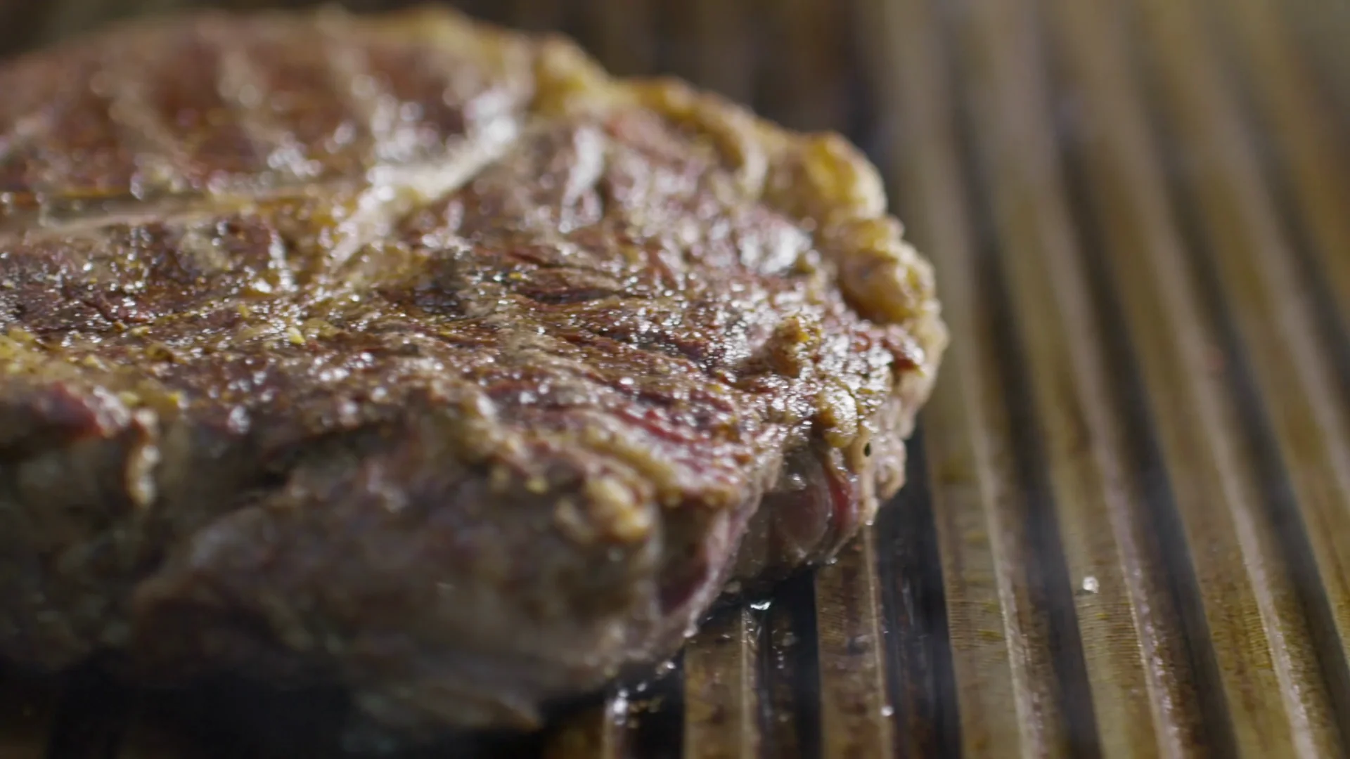 La carne che sfrigola sulla piastra rigata, col fumo che sale
