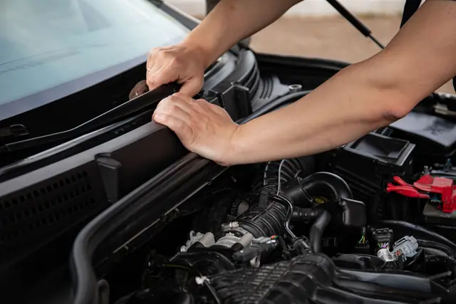 Le mani di un meccanico sul vano motore