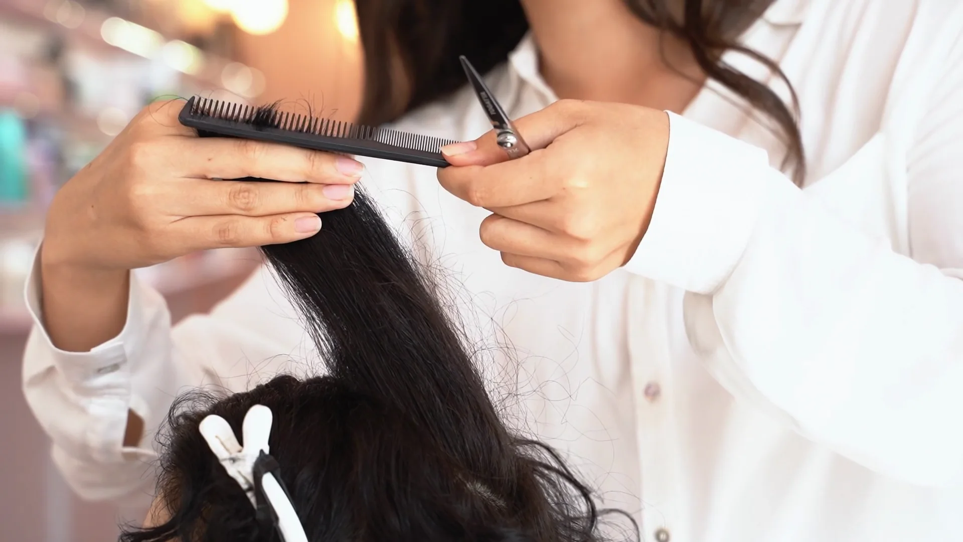 Le mani della parrucchiera col pettine e le forbici sui capelli